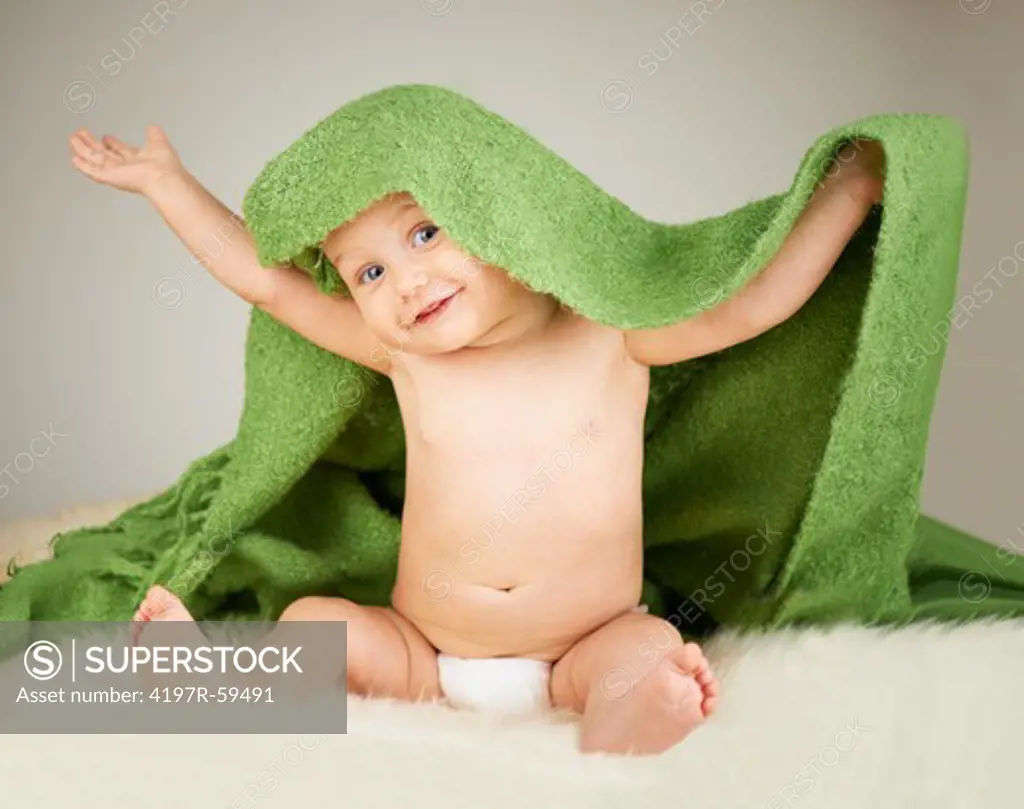 A portrait of a happy baby with a blanket over his head