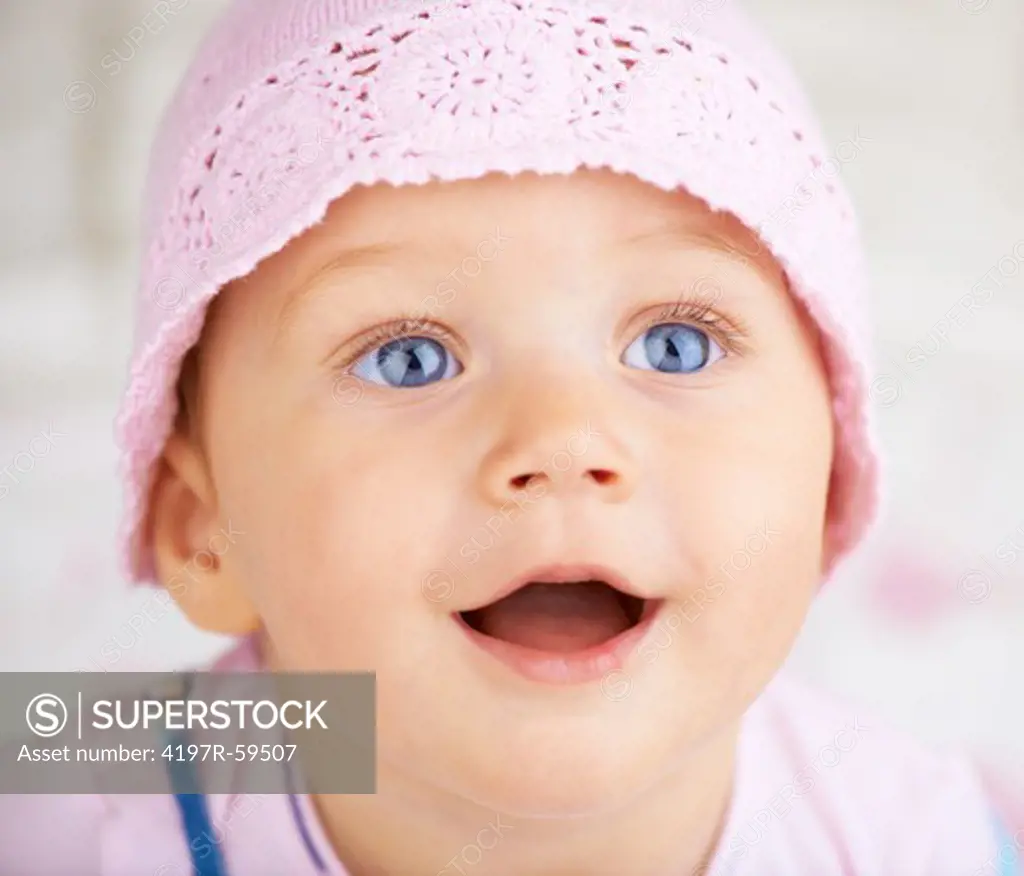 Portrait of an excited baby with a pink hat on