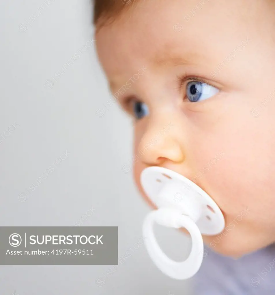 Baby looking to the side with a dummy in his mouth with copyspace