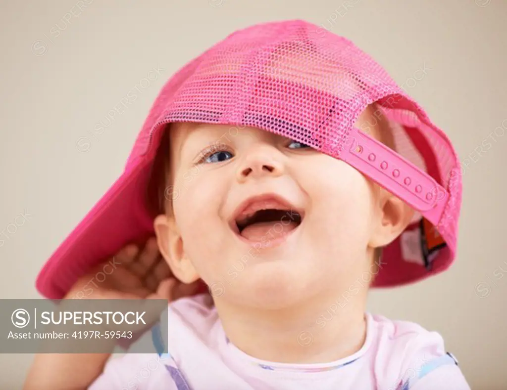 A cute little baby girl wearing an oversized pink hat
