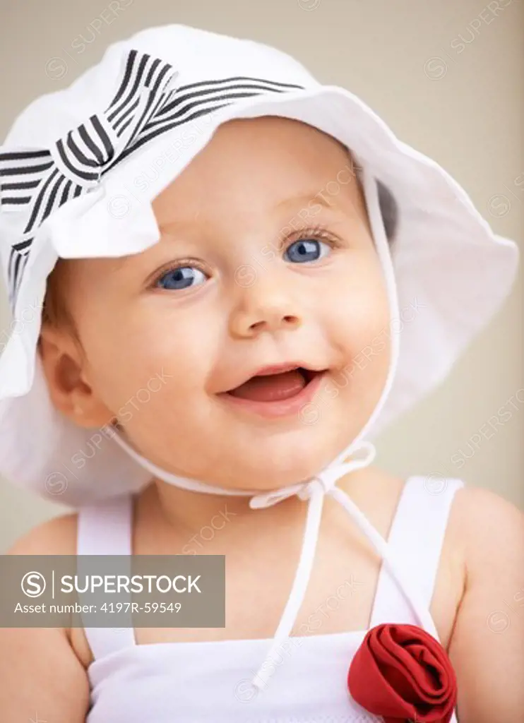 An adorable little girl wearing a hat and smiling at the camera