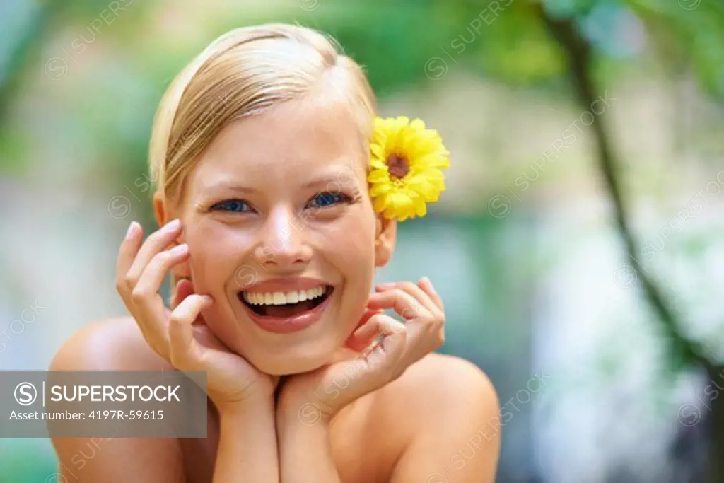 Portrait of an attractive young woman outside with a sunflower behind her ear