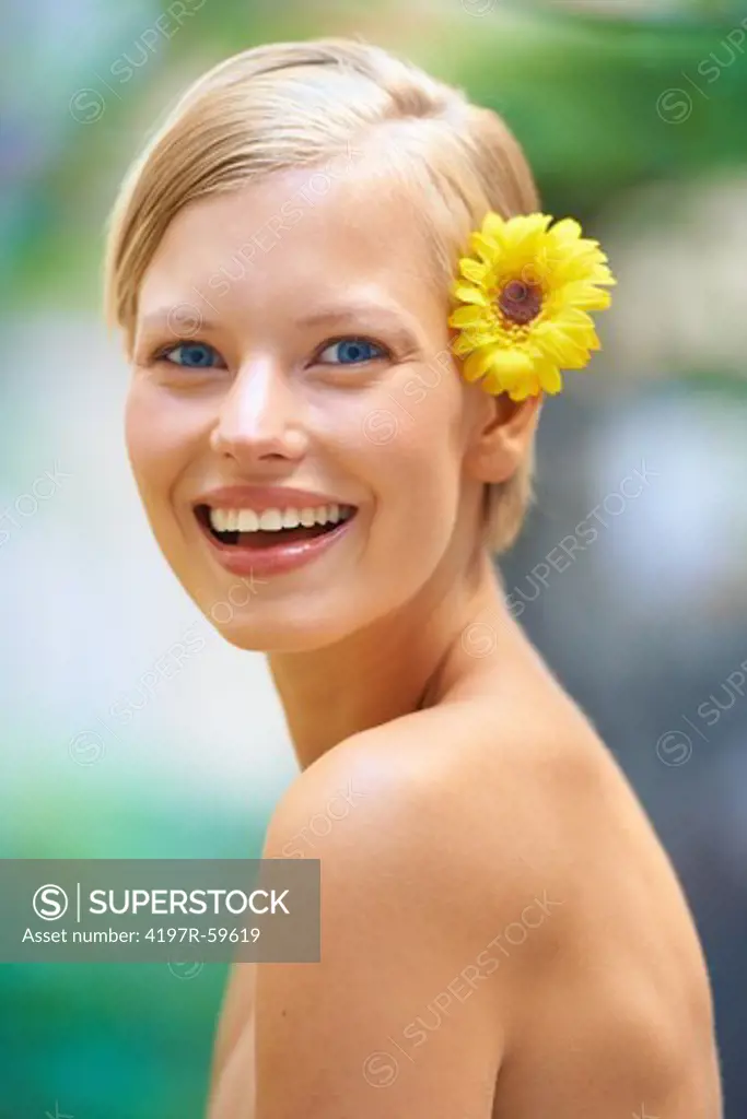 Portrait of an attractive young woman outside with a sunflower behind her ear