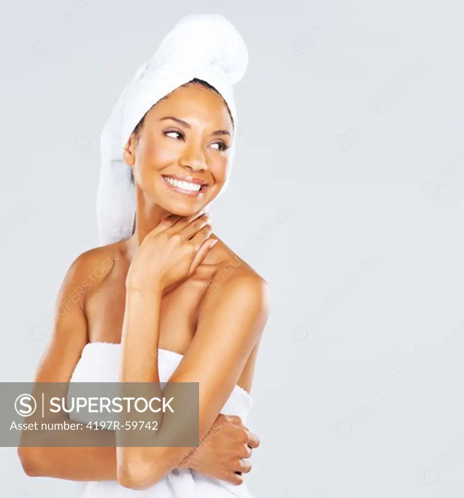 A beautiful young woman wrapped in a towel smiling and looking at the copyspace alongside her