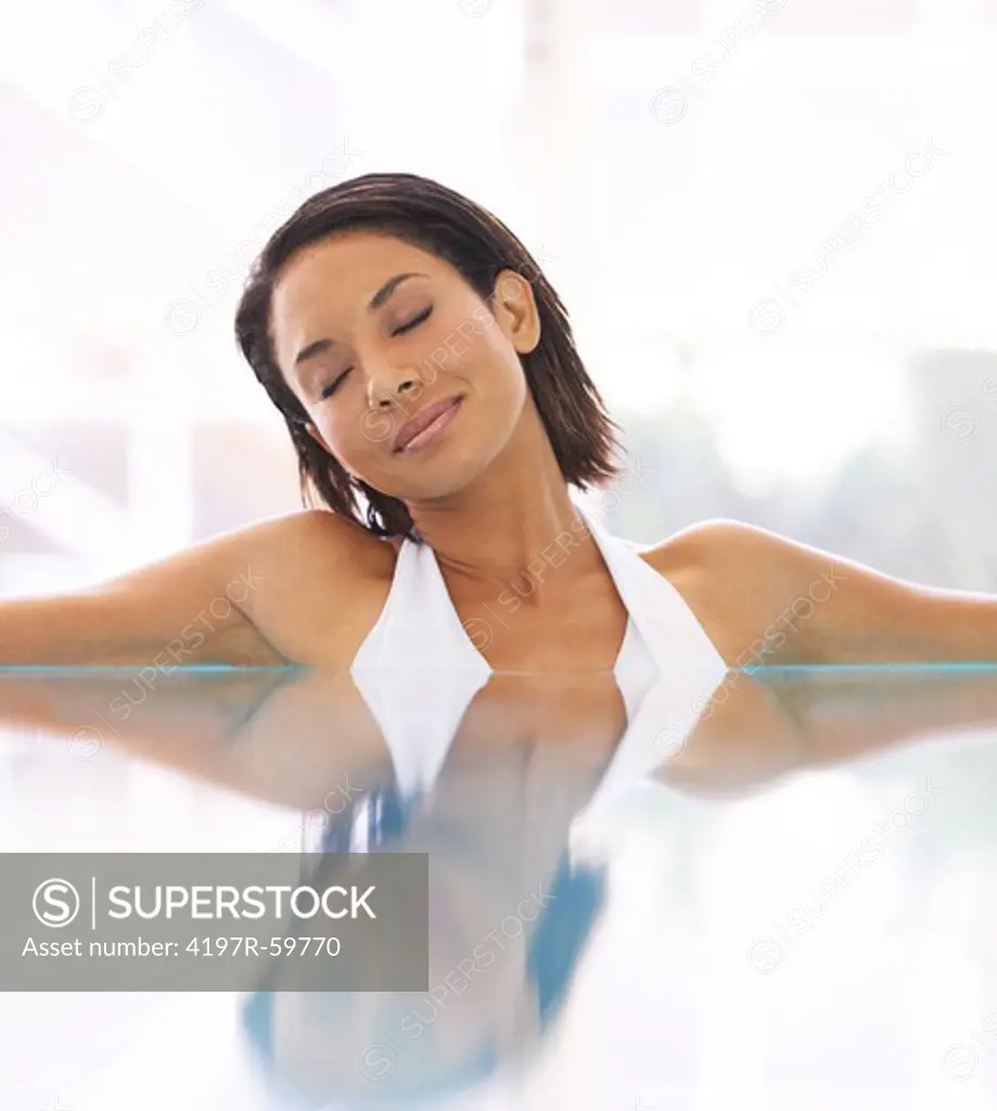 A young ethnic woman sitting in a bath with her eyes closed
