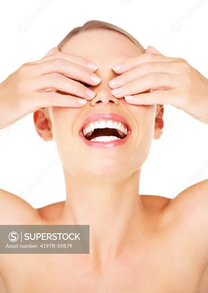 Gorgeous young woman laughing while covering her eyes against a white background