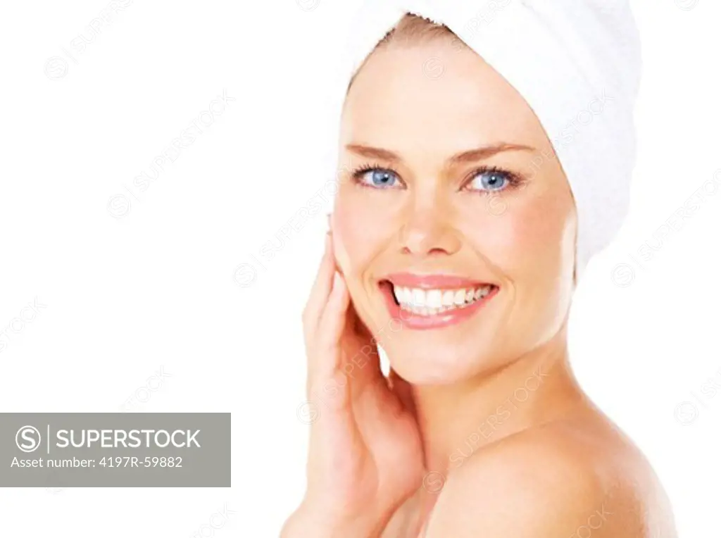 Smiling young blonde woman with a towel wrapped around her head against a white background