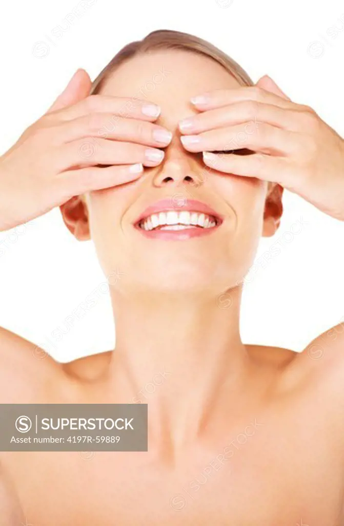 Gorgeous young woman laughing while covering her eyes against a white background