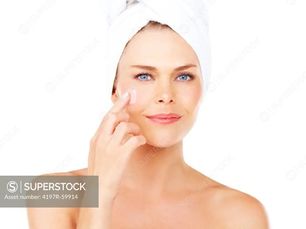 Smiling young blonde woman touching her face with a towel wrapped around her head