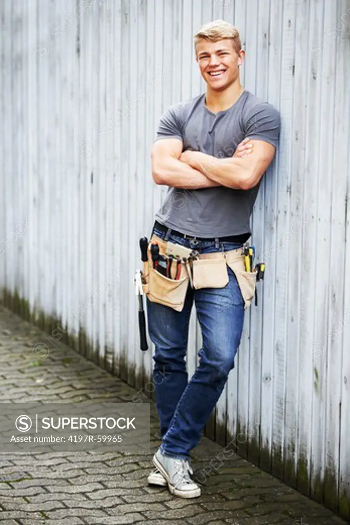 A confident young repairman standing against a fence