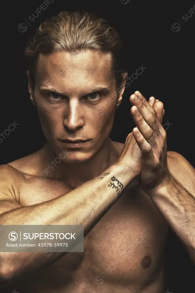 Portrait of a handsome young man with his hands raised on a black blackground