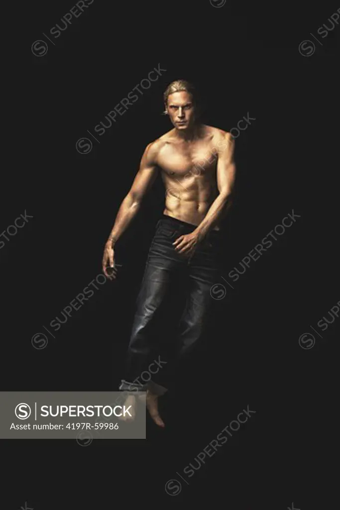 Portrait of a handsome young man wearing only jeans floating on a black background