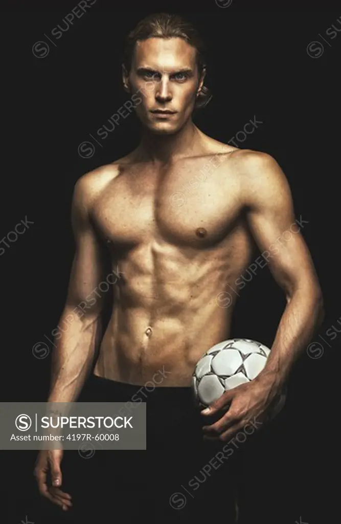 Portrait of a handsome young man holding a soccer ball on a black background