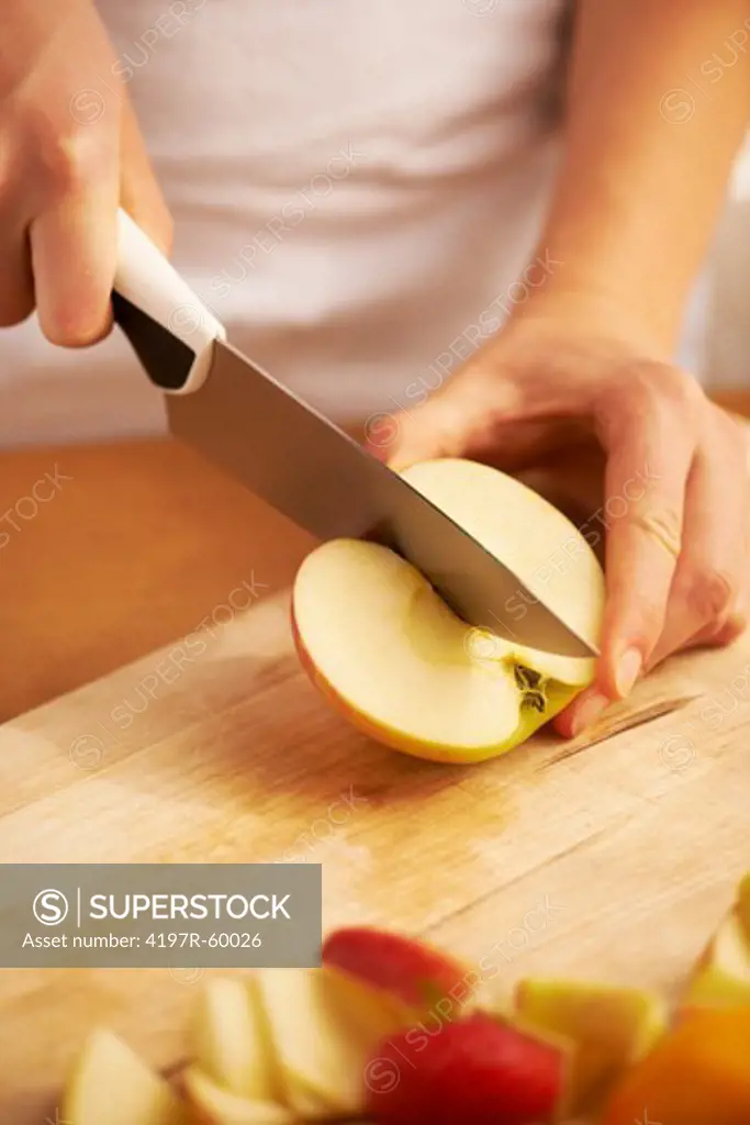 Closeup shot of a cook slicing up an apple on a cutting board surrounded by various fruit