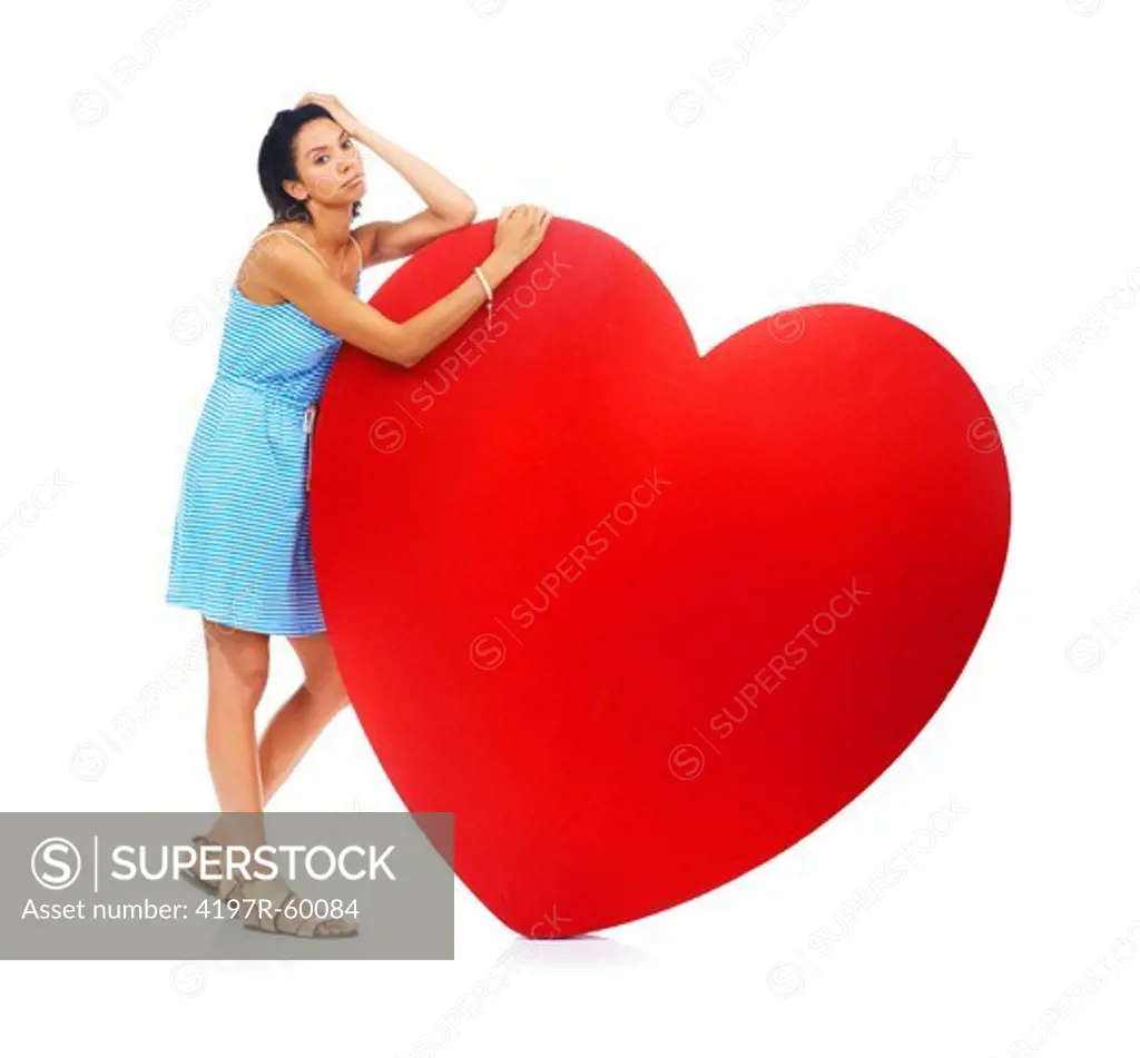 An attractive young ethnic woman looking depressed while standing beside a cardboard heart