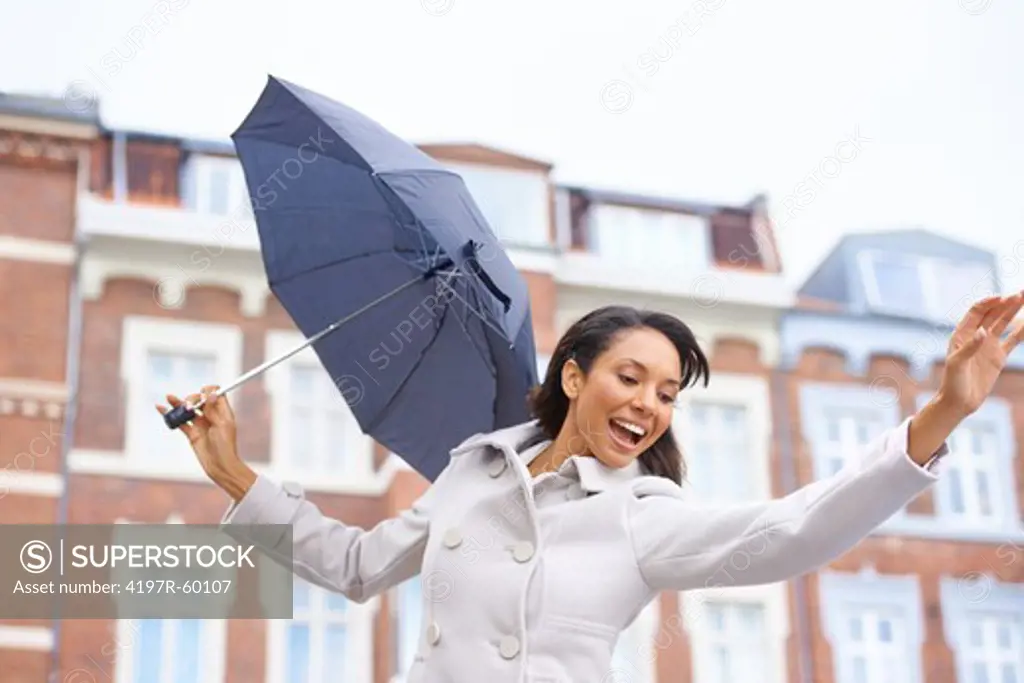 Cute young woman dancing in a new city while holding and umbrella