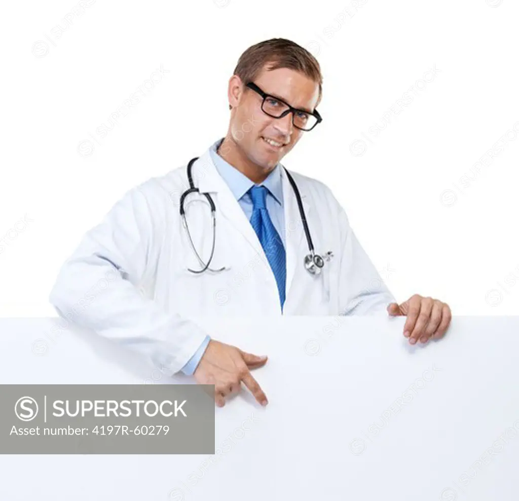Studio portrait of a handsome and confident young doctor pointing towards a blank placard isolated on white