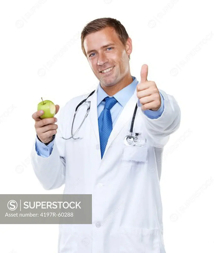 Studio shot of a handsome young doctor holding an apple with a bite taken from it while giving you the thumbs up isolated on white