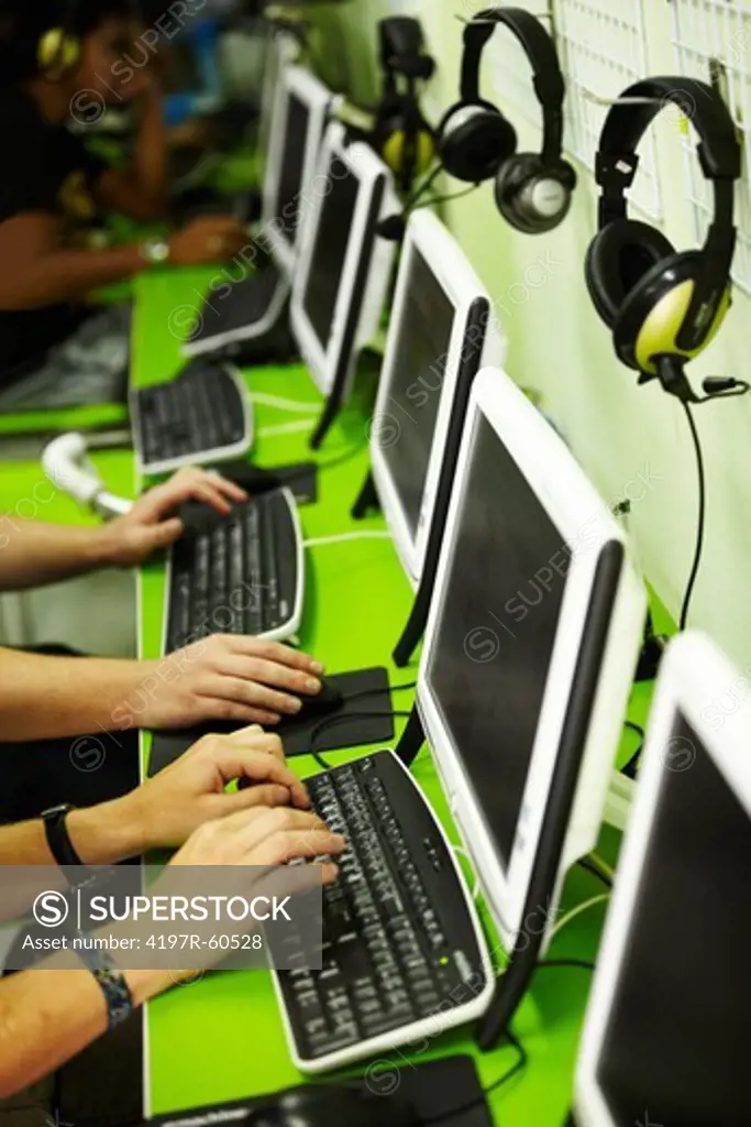 Cropped view of a few men sitting in an internet cafe surfing the net