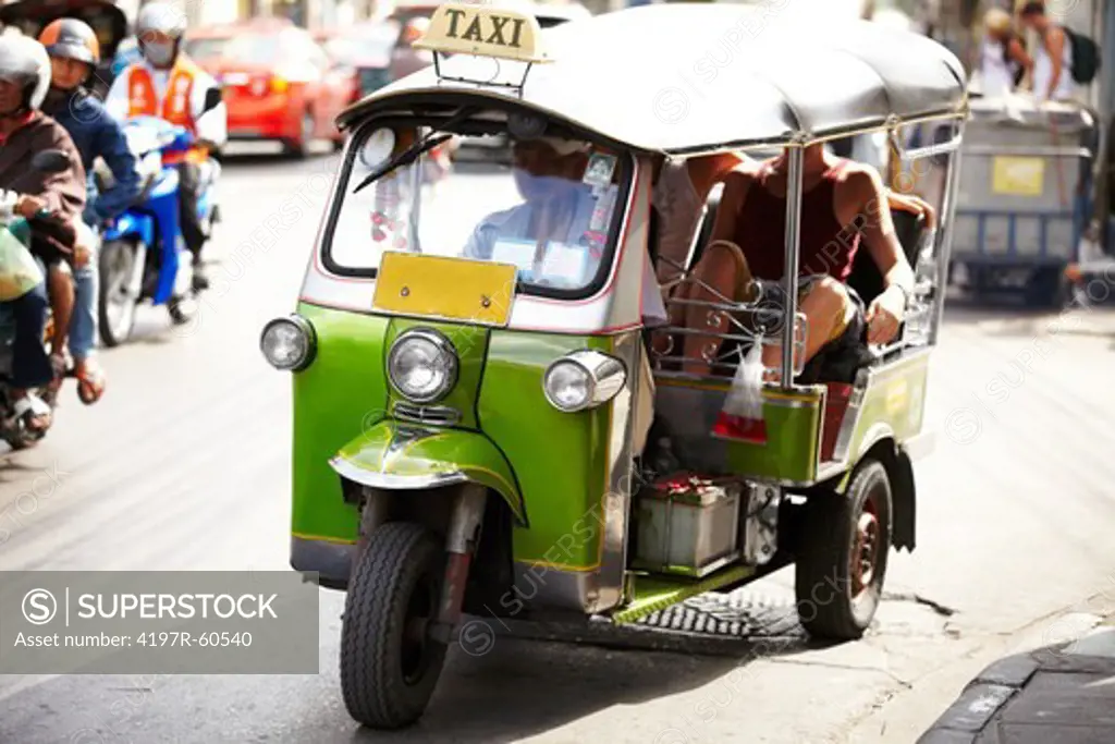 A Thai Tuk-Tuk carrying passengers through the busy Thailand streets