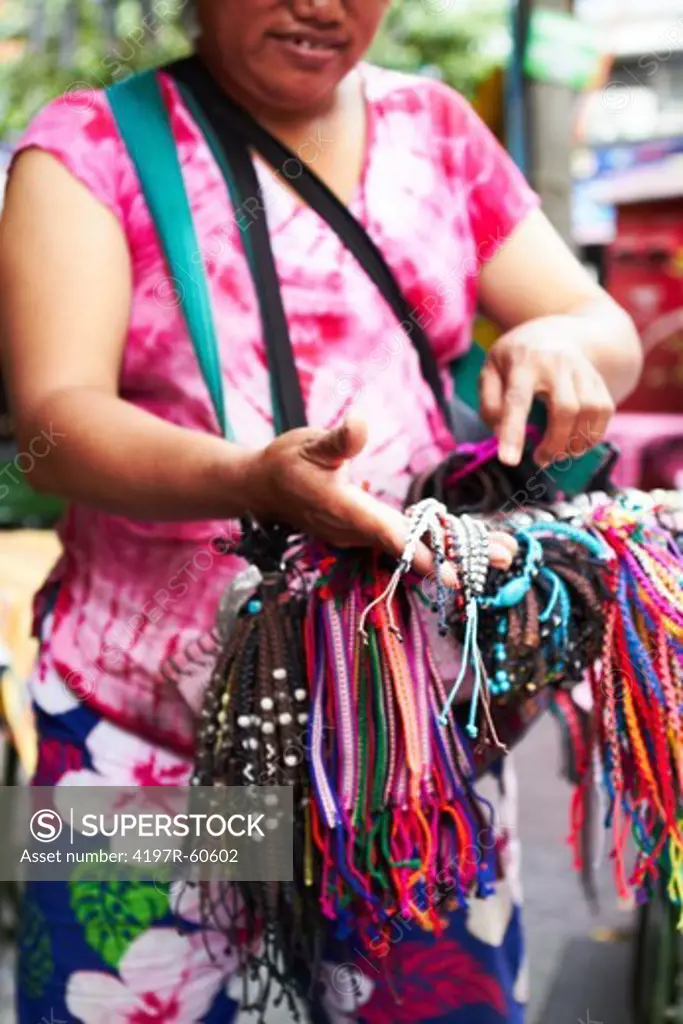 Cropped view of a Thai woman selling bracelets at a market
