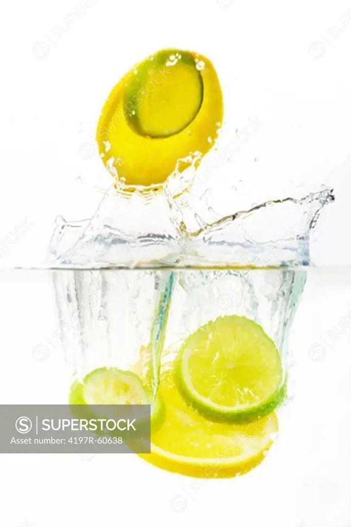 Studio shot of lemon and lime slices being dropped into clear water