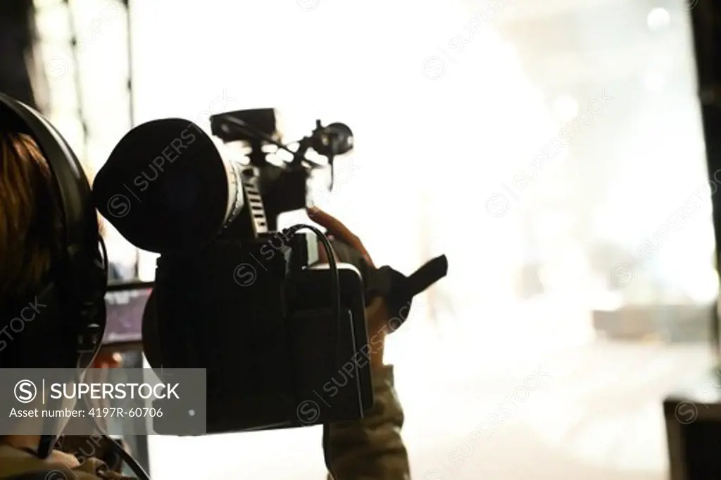 Rear view of a cameraman filming a performance from backstage
