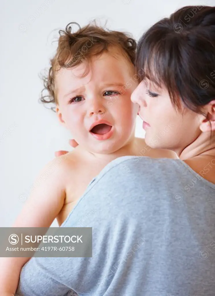 Shot of a mother holding her crying baby and looking concerned
