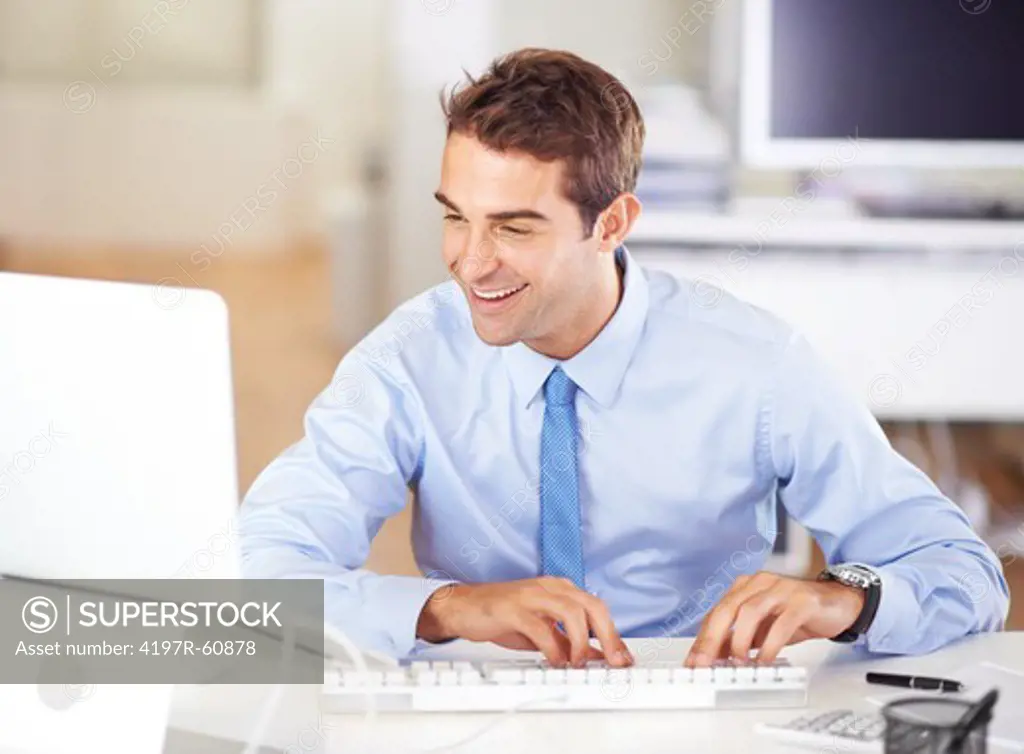 Pleased businessman smiling while sitting at his laptop