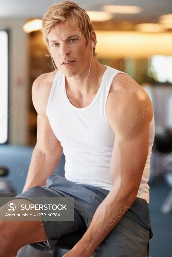 Handsome and muscular young guy sitting in the gym