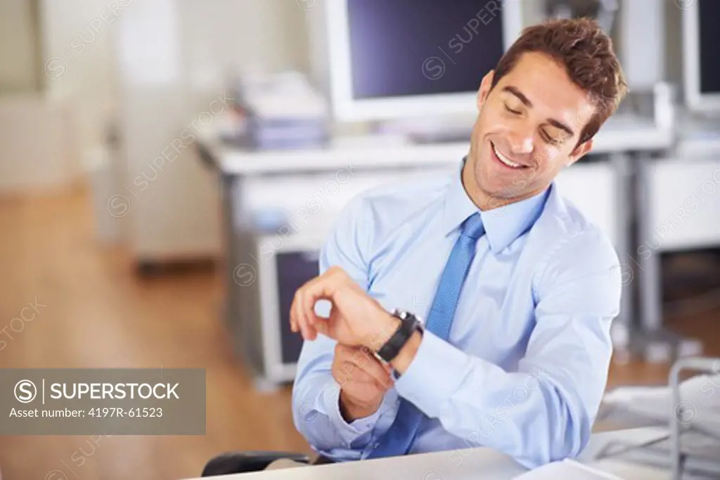 Young businessman looking at his wristwatch with a smile
