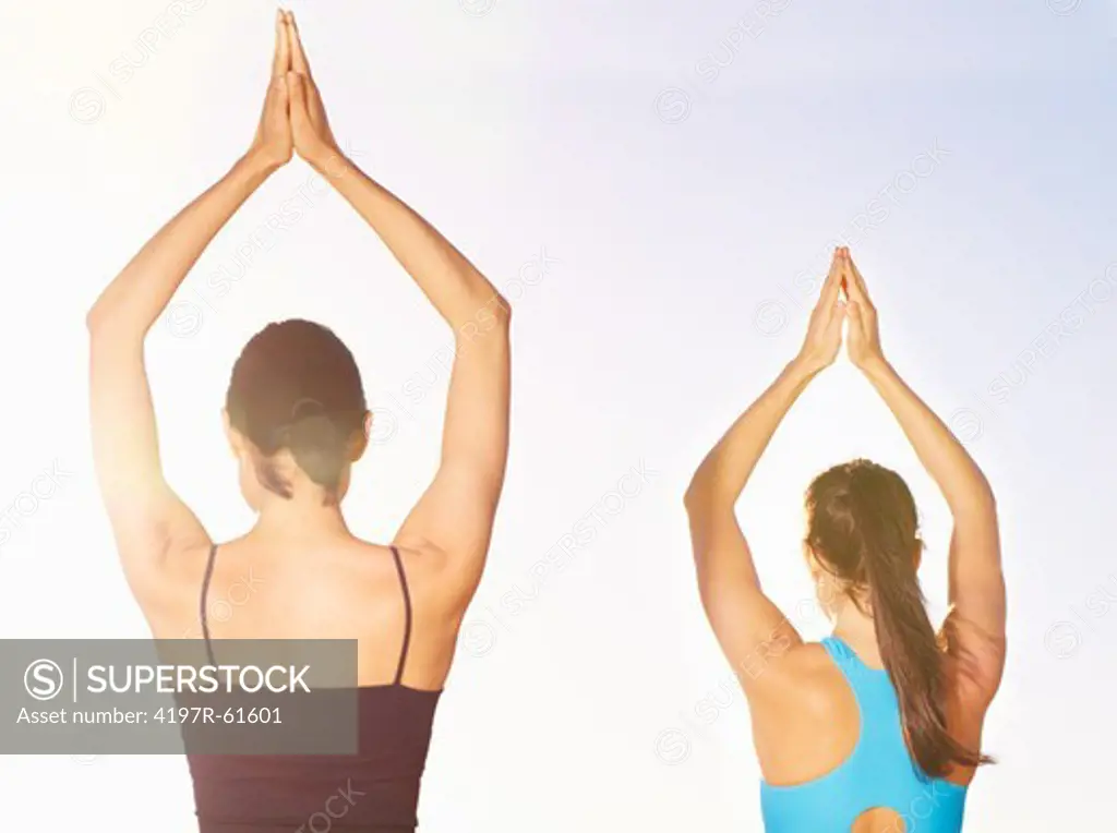 Rear view of two women doing yoga outdoors
