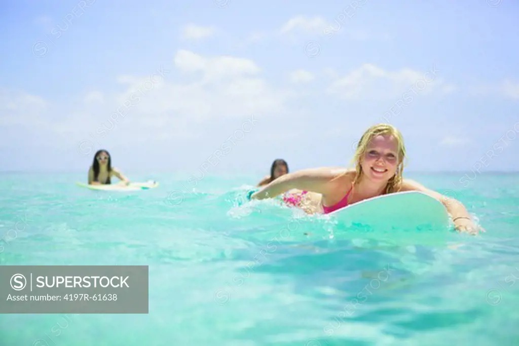 Three young women drifting on surfboards in the ocean - portrait