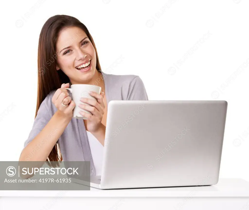 A beautiful young woman sitting infront of a computer and enjoying a cup of tea