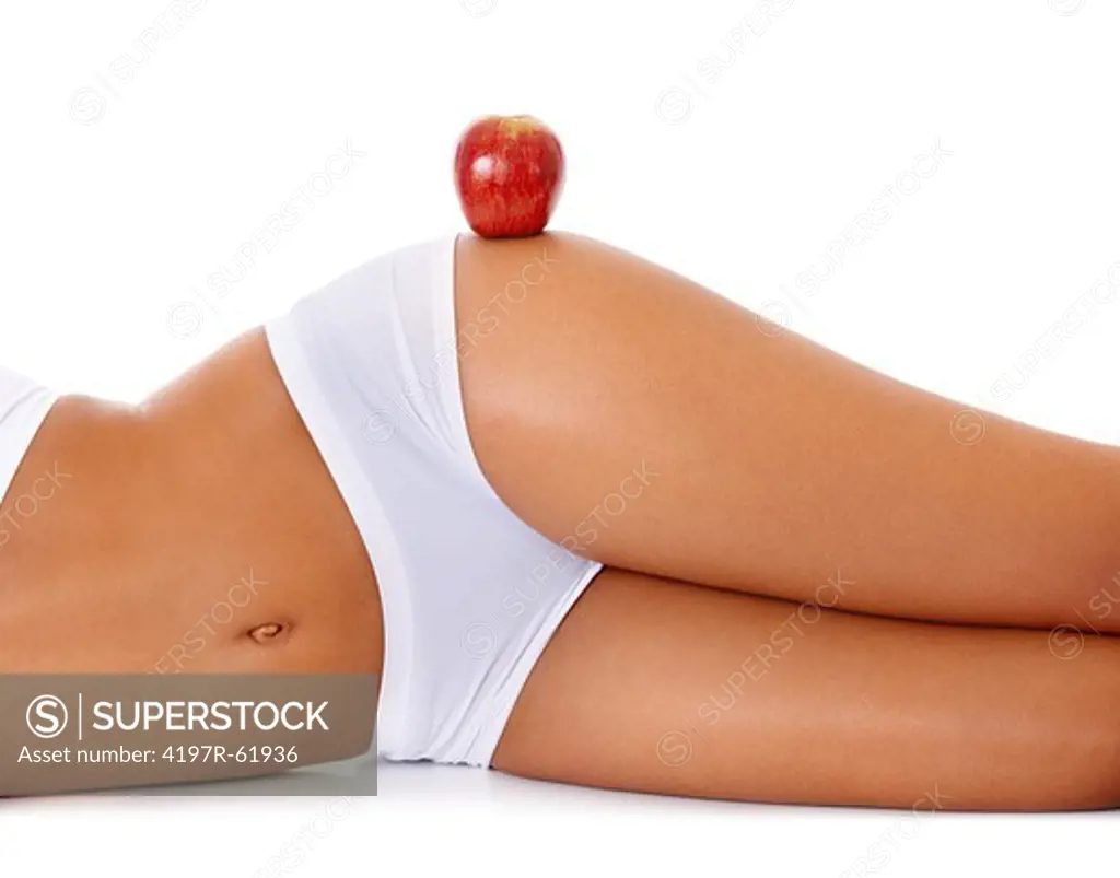 A young woman on her side with an apple balancing on her hip