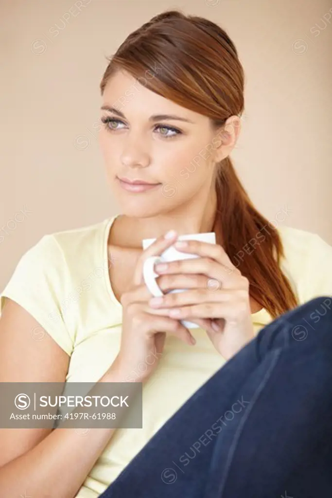 Shot of an attractive young woman sitting and drinking a cup of coffee