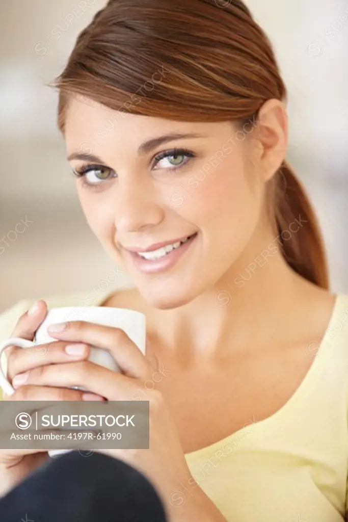 Portrait of an attractive young woman sitting and drinking a cup of coffee