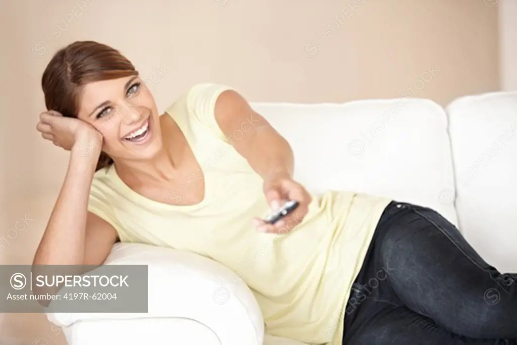 Shot of a smiling young woman changing TV channels with a remote