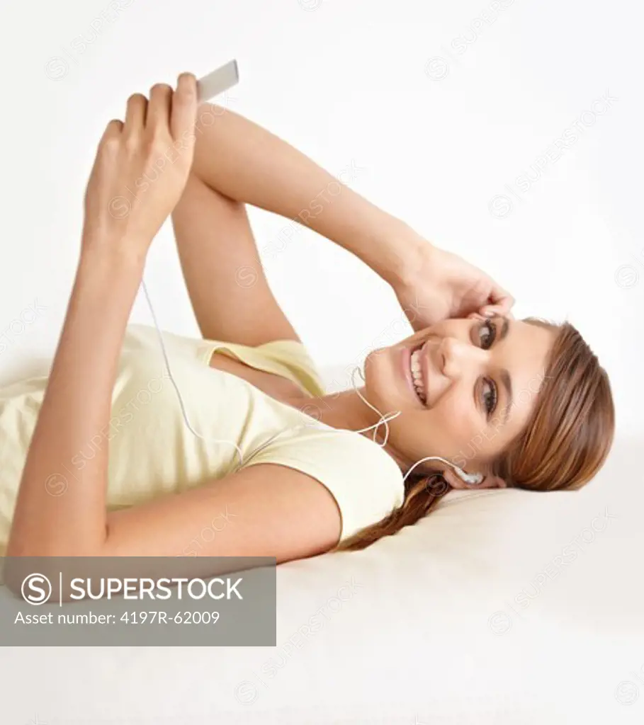 Portrait of a young woman lying on her bed and listening to music on some earphones
