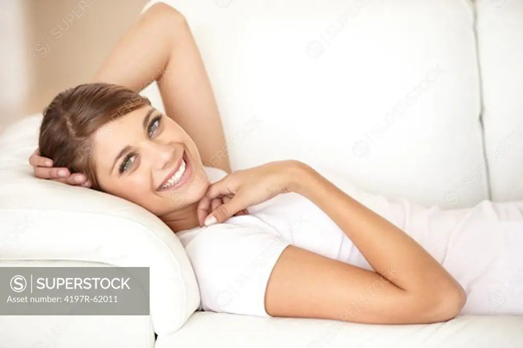 Portrait of a young woman lying on a sofa and smiling at the camera