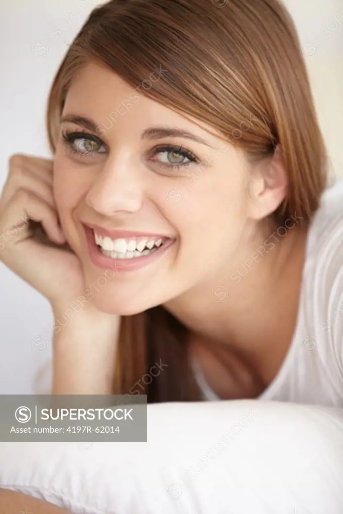 Closeup portrait of a young woman lying on her bed and smiling at the camera