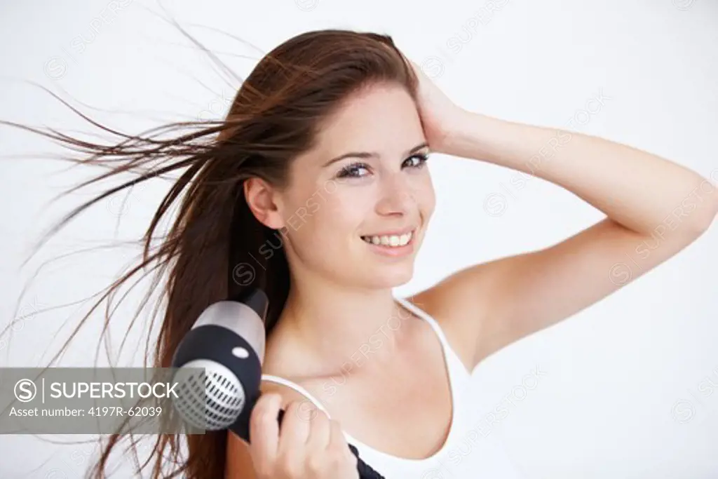 Portrait of an attractive young woman blowdrying her hair