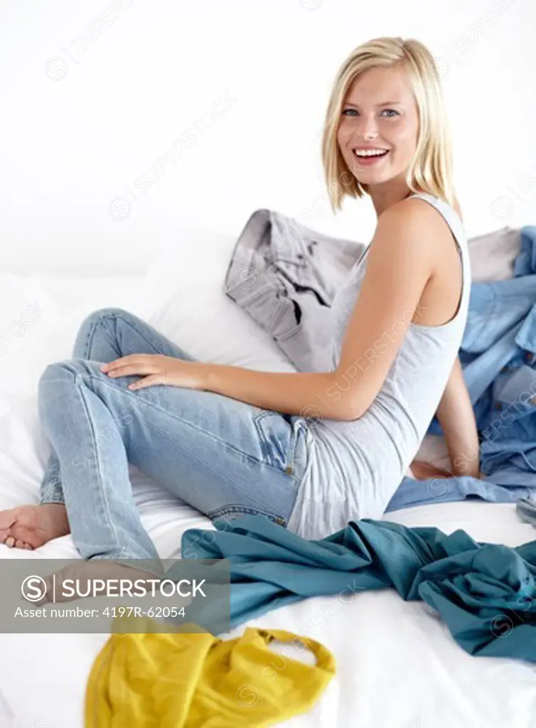 Shot of an attractive young girl lying happily on her bed with clothing strewn about
