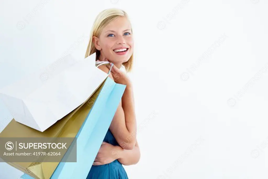 Portrait of a happy-looking young woman with shopping bags slung over her shoulder