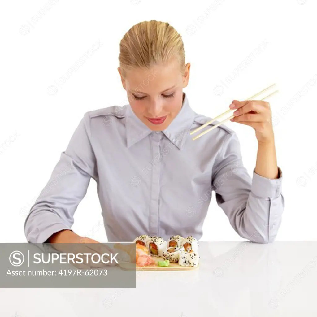 An attractive young woman looking down at the potion of sushi she is eating