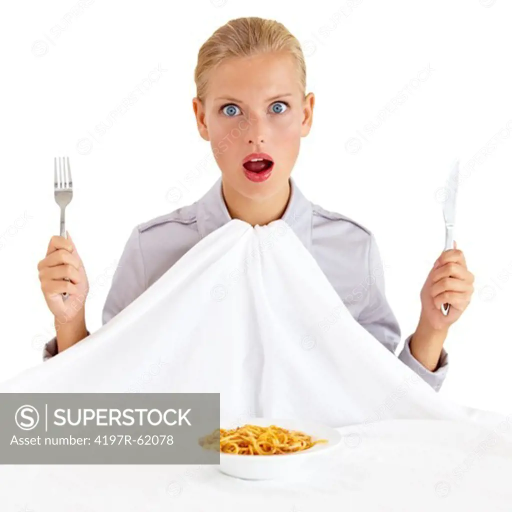 Portrait of a surprised young woman holding a knife and fork with a bowl of paste infront of her