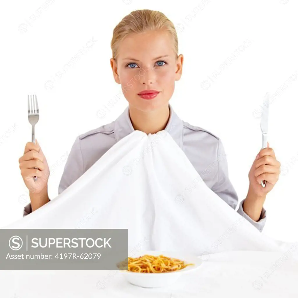Portrait of an attractive young woman holding a knife and fork with a bowl of paste infront of her