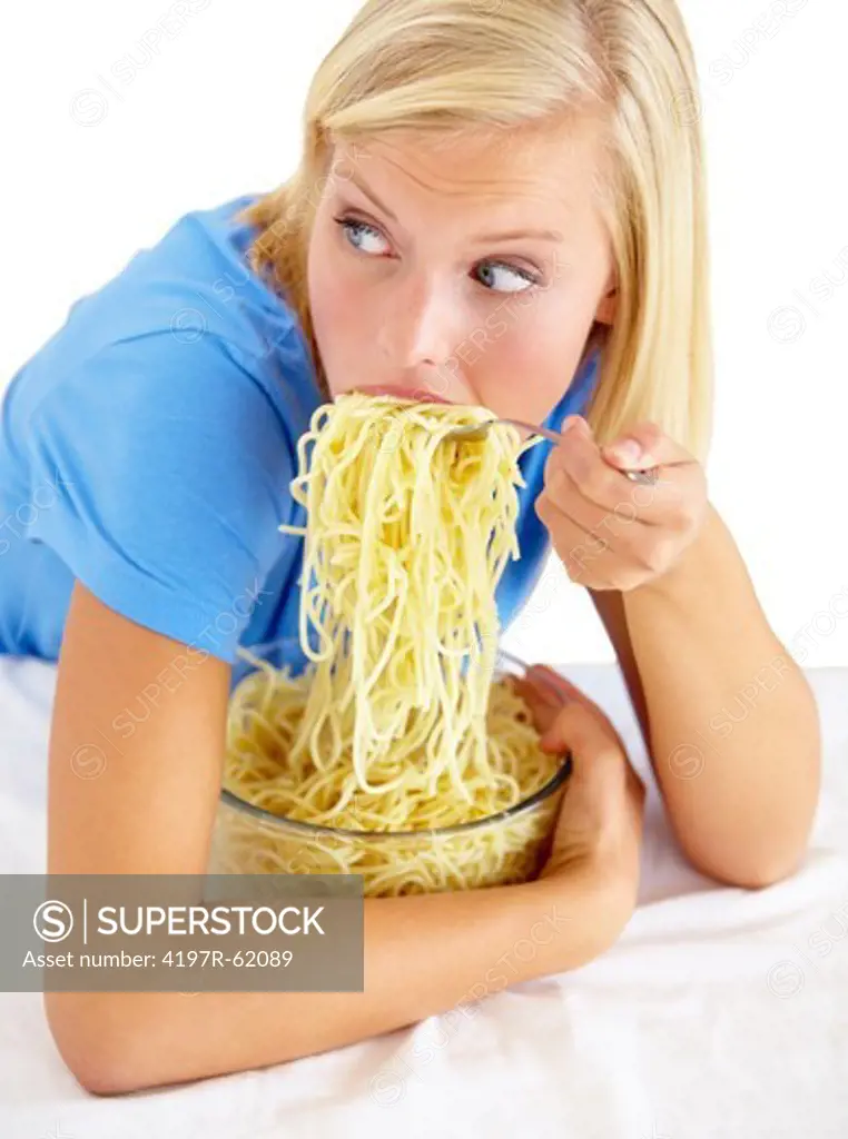A young woman eating an entire bowl of pasta and looking guilty