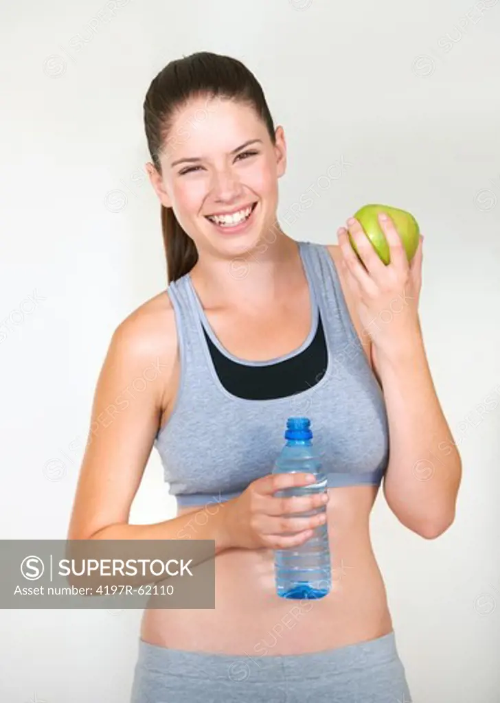Healthy young woman holding a fresh green apple and a bottle of water