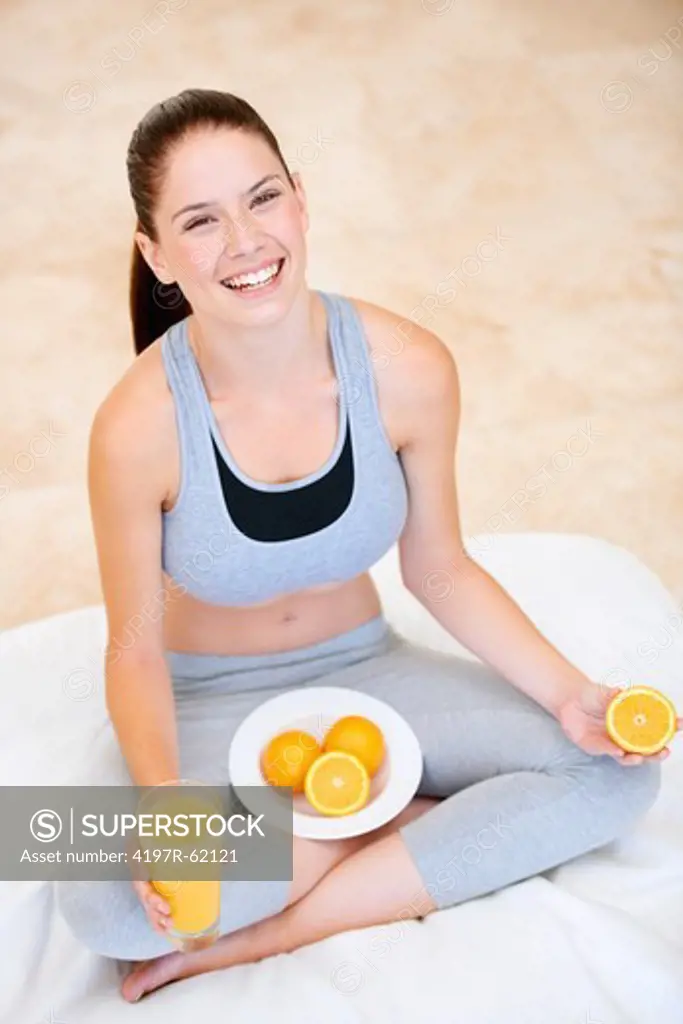 Playful young woman with a glass of orange juice and fresh oranges